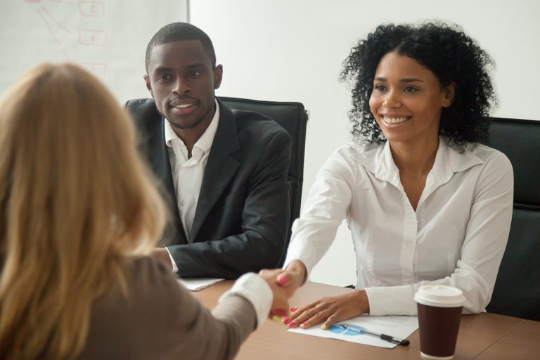 Smiling businesswoman shaking hands with a colleague during a meeting with a male partner.