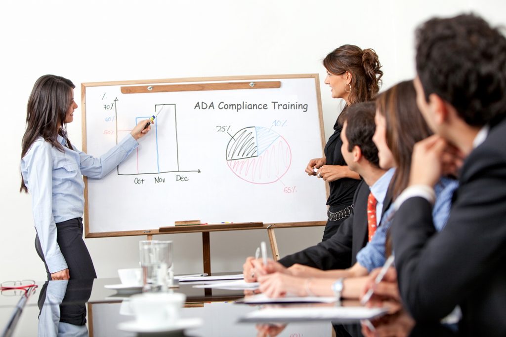 Woman presenting ADA compliance training graphs to attentive professionals.