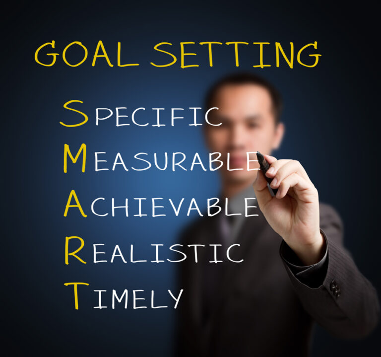 Businessman writing 'Goal Setting' with SMART criteria on a clear screen, teaching effective planning.