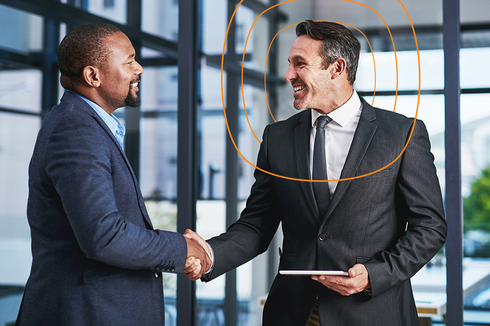 Two business professionals shaking hands in a modern office, symbolizing successful partnerships and collaboration.